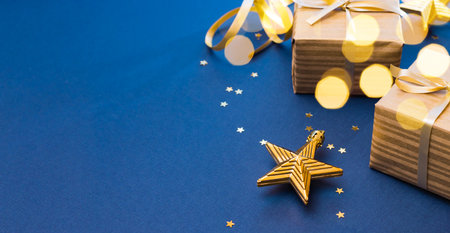 Christmas composition with golden gift box and Christmas decorations, garland on a blue background. Winter holiday background with copy spaceの写真素材