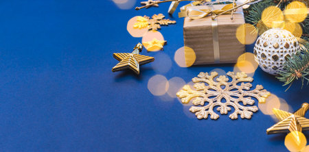 Christmas composition with fir branches and Christmas ball, garland, gift box on a blue background. Winter merry christmas holiday greeting cardの写真素材