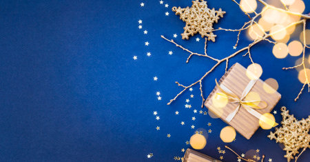 Flat lay christmas composition with golden gift box and christmas decorations, garland on a blue background. Winter holiday background with copy spaceの写真素材