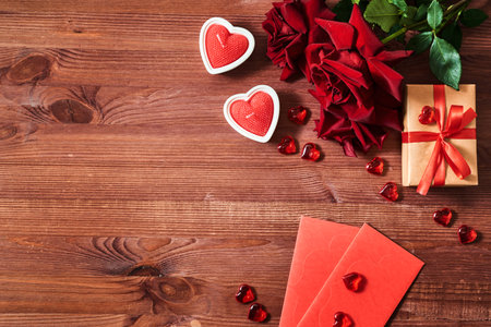 Valentines day frame with gift box and red roses, candles on a wooden background. Valentines day banner with copy spaceの写真素材