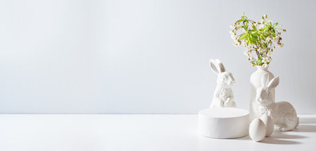 Empty round white podium for product presentation. Spring flowers in a vase and easter eggs on a light backgroundの写真素材
