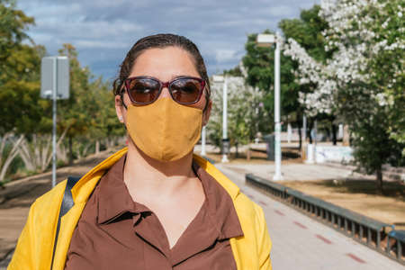 Attractive woman with face mask with a yellow jacketの写真素材