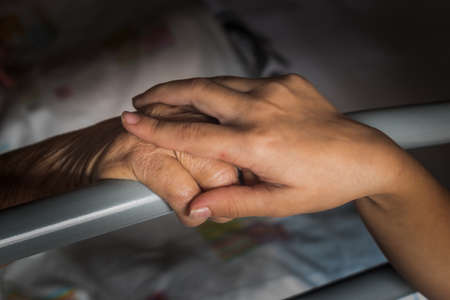 granddaughter holding the hand of her sick grandmotherの写真素材