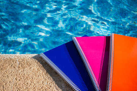 colored notebooks next to a pool