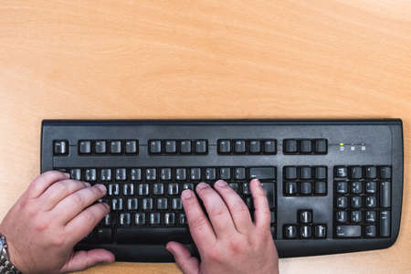 male hands on a black keyboard, isolated on brown