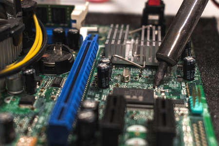 close up of a IT technician soldering a part of a computer motherboard in an office