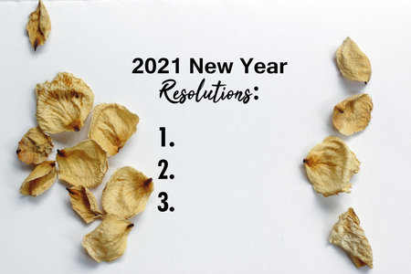 2021 New Year Resolutions list with numbers and dried white rose petals frame decoration on white...