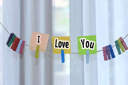 I love you. Text message on colorful paper notes with clips hanging on rope on white  background. Notes on sticky note showing love and care to self or someone.の写真素材