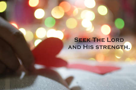 Christianity inspirational quote - Seek The Lord and His strength. Bible motivational words with blurry background of hand holding red love heart paper shaped, on colorful bokeh light background.の写真素材