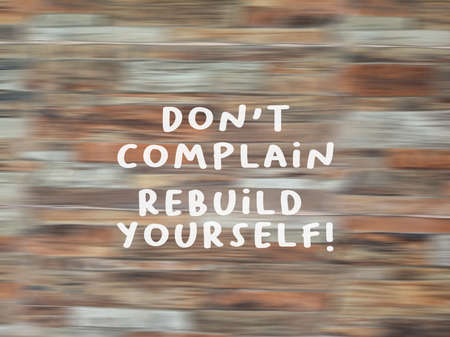 Motivational quote - Don't complain, rebuild yourself. Sign on blurry wooden pattern texture...