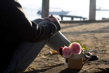 Person sitting alone with roses and coffee cup on daydreaming at sunrise.の写真素材