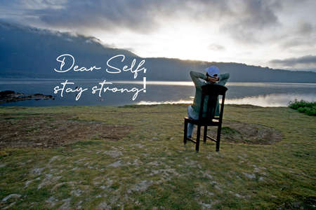 Self love care concept with inspiraitonal motivational words - Dear self, stay strong. With a woman relax on chair enjoying blue lake view in the morning.の写真素材