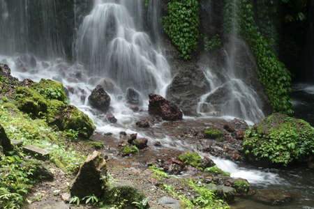 Waterfall with smooth water flow to the river. Bali nature waterfalls in the forest.