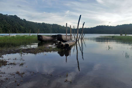 Wooden fishing boats in the lake, with blue sunrise sky colors. Tranquil morning view with green grass on the water. Nature landscape background.の写真素材