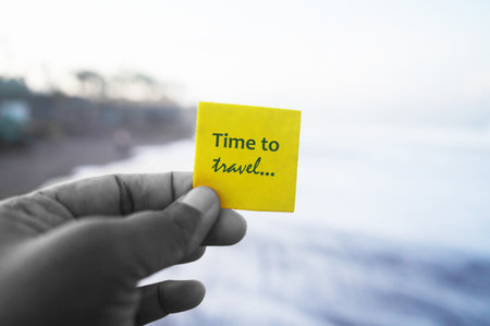 Person holding a yellow card with a text in hand - Time to travel. Self reminder for recharge....