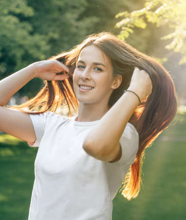 Portrait of one young beautiful European brunette in a white t-shirt with long hair. Sexy carefree...