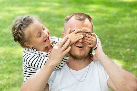 Family time. Father and daughter together. The girl covered her father's eyes with her hands. Surprise and surpriseの写真素材