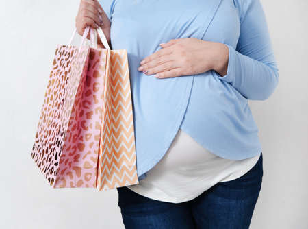 Young Caucasian woman with shopping bags in her hands, isolated on a white background. Close - up of stomach and hand with bagsの写真素材