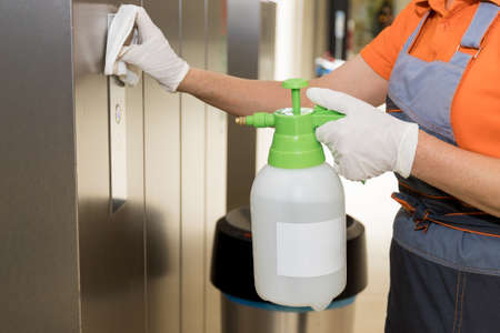 A woman at work wearing gloves. A professional cleaner cleans the business center. Sterilization of walls and Elevator in the shopping center.の写真素材