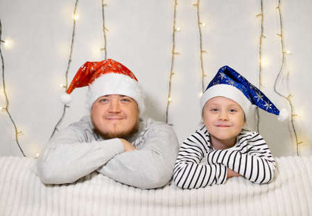 happy family father and child little daughter sitting on the sofa in Santa hats waiting for the Christmas miracle and new year's giftsの写真素材