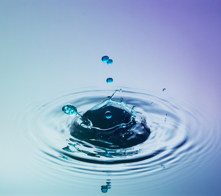 Water drop photography, one or two drops of water dropped from height into a tray filled with water and captured as they hit the water or collide with each other.の写真素材