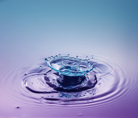 Water drop photography, one or two drops of water dropped from height into a tray filled with water and captured as they hit the water or collide with each other.の写真素材