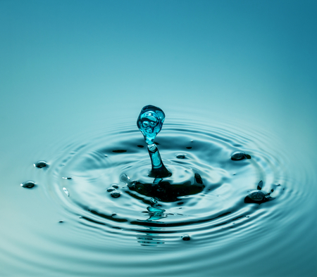 Water drop photography, one or two drops of water dropped from height into a tray filled with water and captured as they hit the water or collide with each other.の写真素材
