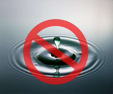 A drop of water plopping into water with a red circle and diagonal line across, representing a no access traffic sign, to indicate no access to water.の写真素材