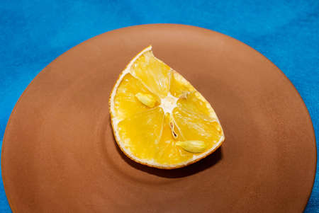 A half-dried piece of lemon that lies on a saucer on a blue background. Selective shot.の写真素材