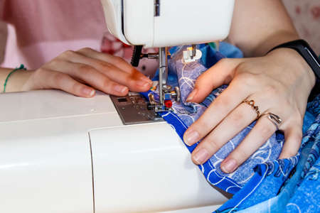 Women's hands that sew a fabric product on a sewing machine. Close up.の写真素材