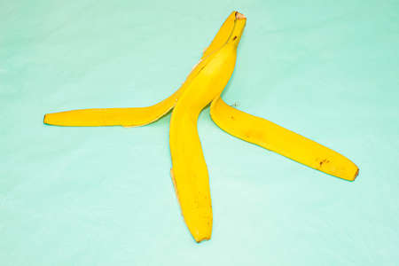 Yellow banana peel on a turquoise background. Close up.の写真素材