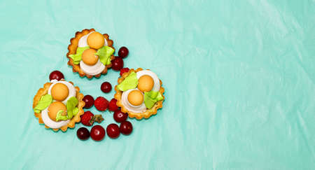 Cake-baskets, next to which are fresh raspberries and cherries. Horizontal frame, top view.