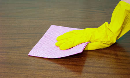A woman's hand in a rubber glove wipes the dust from the surface with a napkin. Close up.