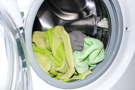 An open washing machine with dirty Laundry embedded in it. Close-up, selective focus.
