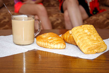 A Cup of tea with milk and various pastries on the table during tea. The people in the background....