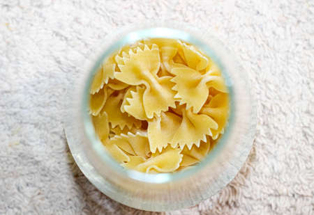 Farfalle macaroni in a glass container on the table. Close up.