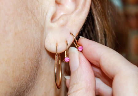 Three gold earrings in one female ear. Close up.の写真素材