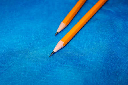 Two sharpened simple pencils lie on a blue background. Close-up, selective shot.の写真素材