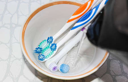 Several toothbrushes in a Cup are filled with boiling water for disinfection from viruses and...