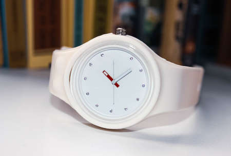 White wrist watch with hands and dial close-up on a white table. Time is money.