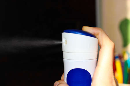 The hand sprays deodorant into the air by pressing it.