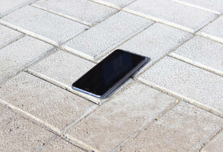 The lost smartphone is lying on the sidewalk. Carelessness.