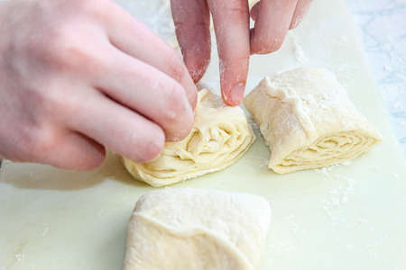Women's hands from yeast dough cook buns of different shapes. Home baking.