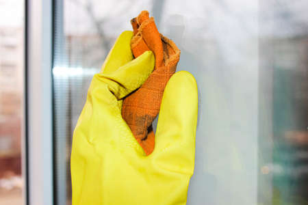 A woman's gloved hand washes a dirty window. Useful household chores.