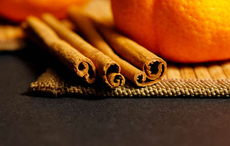 Cinnamon sticks on a dark background with tangerines in the background. Close-up, selective shot.の写真素材