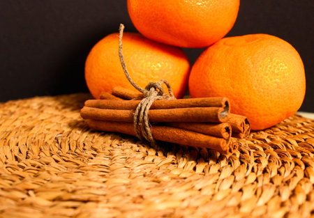 Cinnamon sticks tied with twine and tangerines on a dark background. Close-up, selective shot.の写真素材
