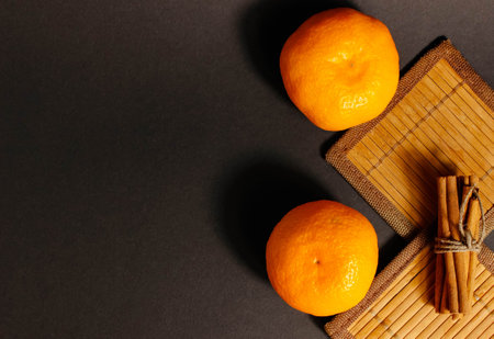 Whole tangerines on Beermat on the table, with cinnamon sticks next to them. Top view, selective shot, copy space.の写真素材
