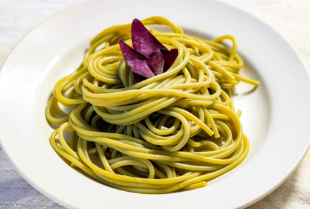 A dish of green spinach cooked spaghetti on a white plate. Selective focus.の写真素材