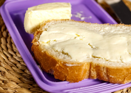 Cut off a piece of white loaf with butter. sandwich for breakfast. Close-up.