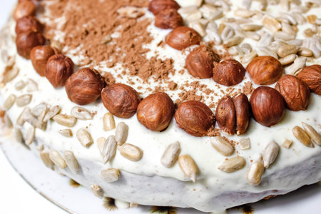 Homemade cake decorated with hazelnuts, seeds and cocoa. Selective shot, close-up.の写真素材